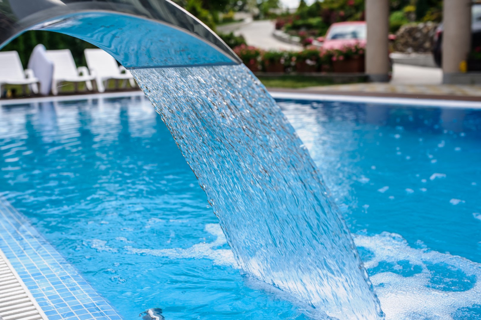 View of a empty swimming pool with blue water outside. Light day and clean background outside in the garden.